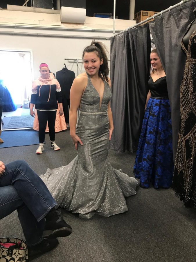 Sadie Bastardo tries on a metallic dress with an extended tail. She could definitely make an entrance with this one! This dress can be found at TeraLees Formals in Osceola, Indiana.
