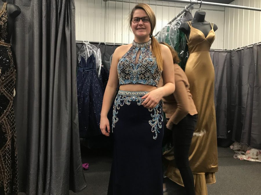 Senior Emma Jarrett tries on a black two piece with blue jewels on the top piece that flow into the tight fitted bottom piece. This dress can be found at TeraLees Formals in Osceola, Indiana.