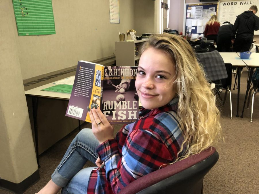 Junior Rayna Minix holds up her most recently read book, Rumble Fish by S. E. Hinton.