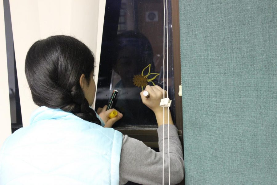 Senior Sharon Campencho, is drawing a flower on the window??