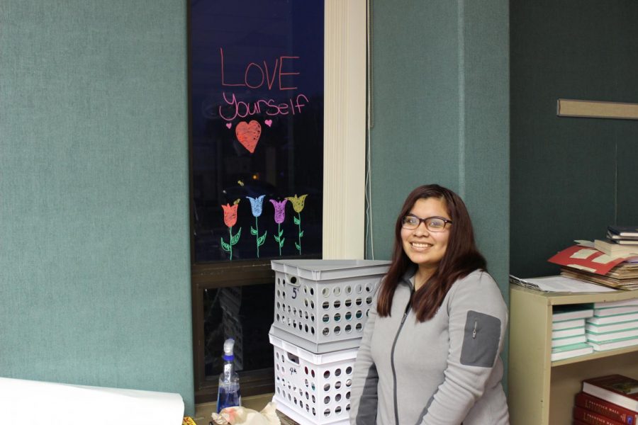Sophomore Jessica Meza poses next to her drawing during 5th hour on Wednesday, Feb. 5. Her hope was that the flowers and her message would spread a positive attitude throughout the room.
