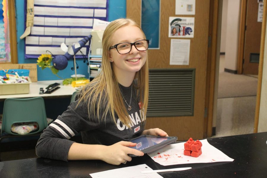 Junior Chloe Sharp poses with her structure pf stratified cuboidal epithelium tissue she built out of clay on Monday, Nov. 4.