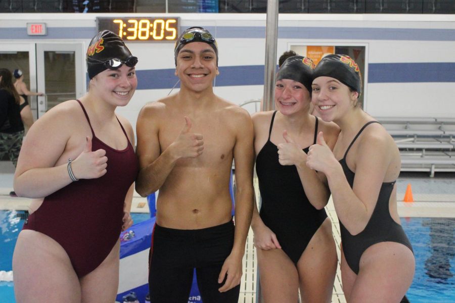 Senior Lilly Spray, Junior Luis Cruz Portillo, Sophomore Kailey Gregg, and Junior Gabby Scott smile for a group picture before warm-ups on Thursday, Jan. 2 at the Elkhart Aquatics Center.
