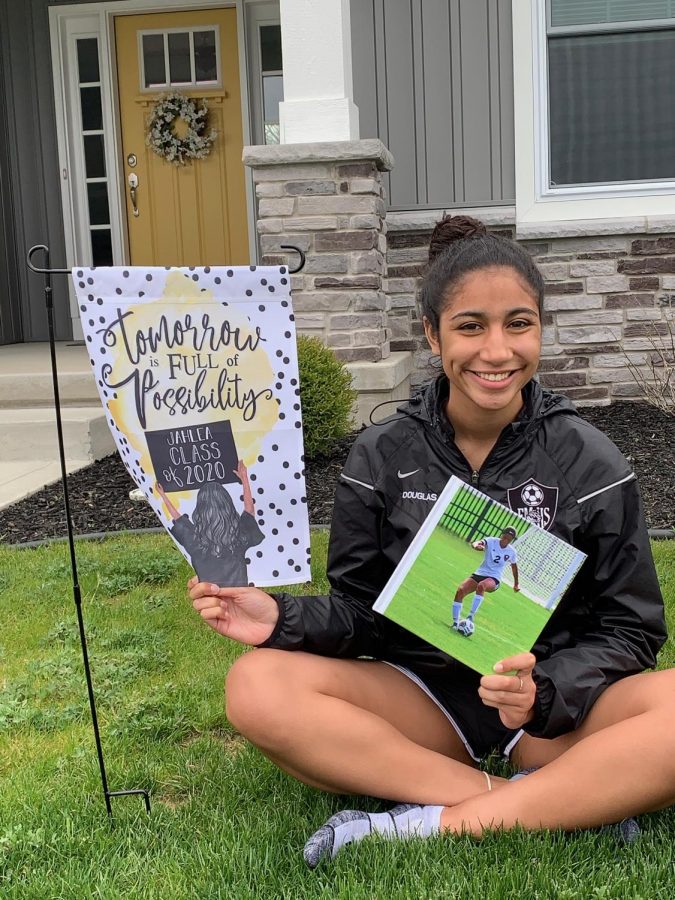 Senior, Jahlea Douglas, poses with her photo book and senior flag purchased by her adopted senior. Adopt a senior is a facebook group that many schools have created to recognize seniors. 