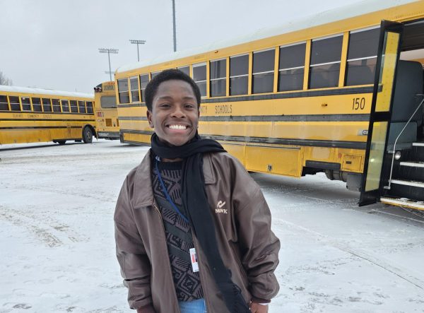 A student organizer poses in front of a bus.